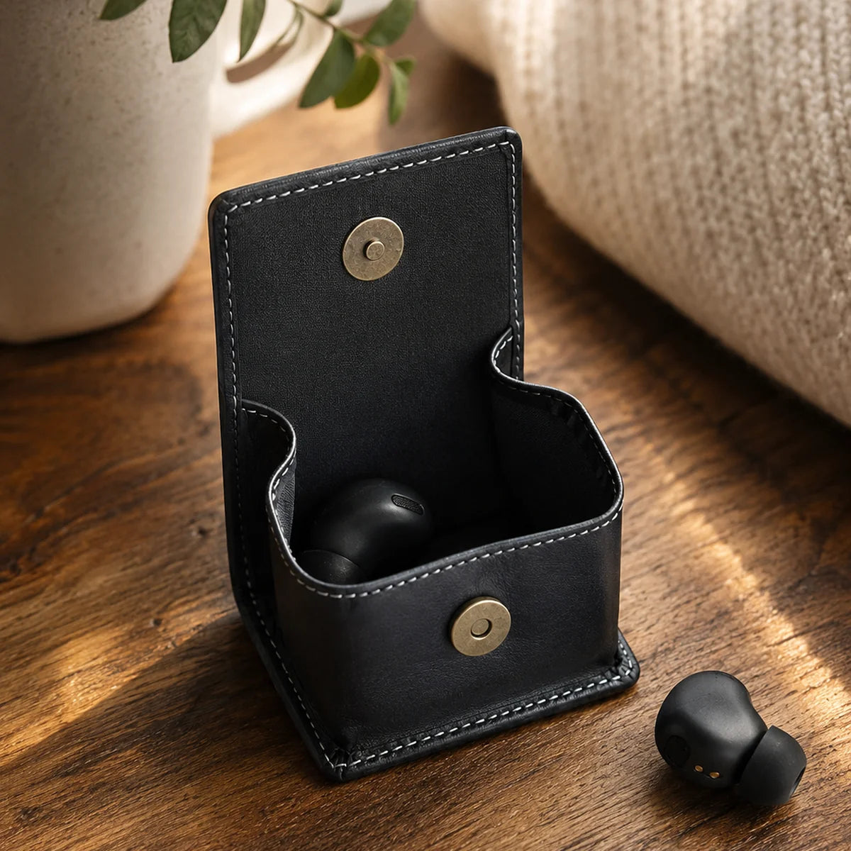 Open black leather coin purse used to store wireless earbuds
