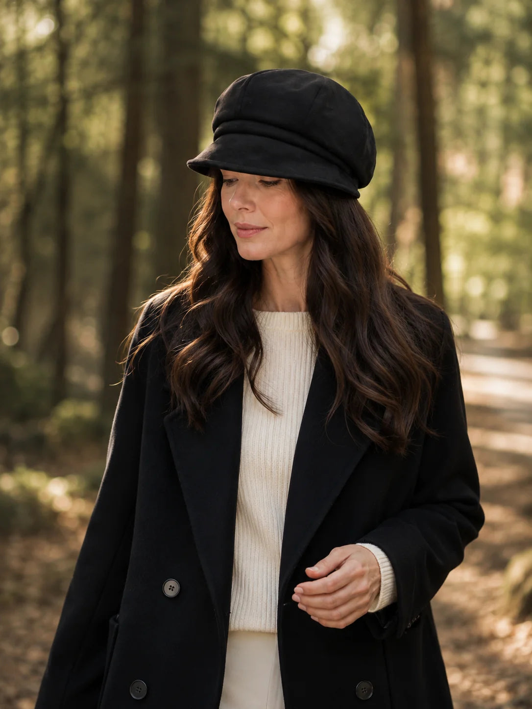 Woman wearing a black paneled beret cap on a wooded path