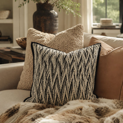 Herringbone cushion layered with neutral textiles on a sofa