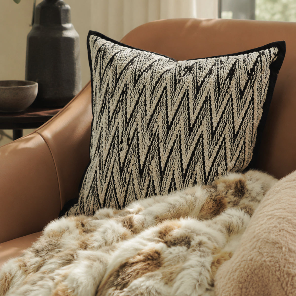 Black and white herringbone cushion styled on a leather chair