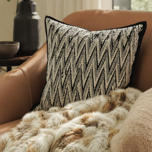Black and white herringbone cushion styled on a leather chair
