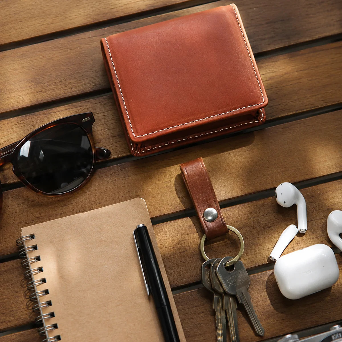 Brown leather coin purse styled with keys, earbuds, notebook, and sunglasses