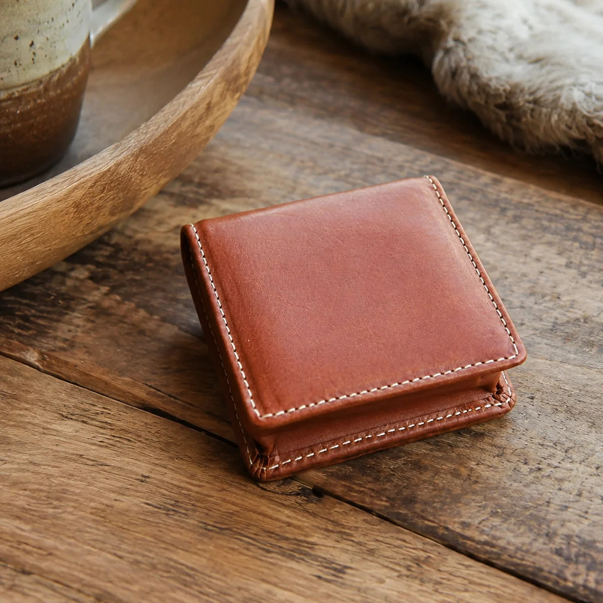 Brown leather coin purse styled on a warm wood table