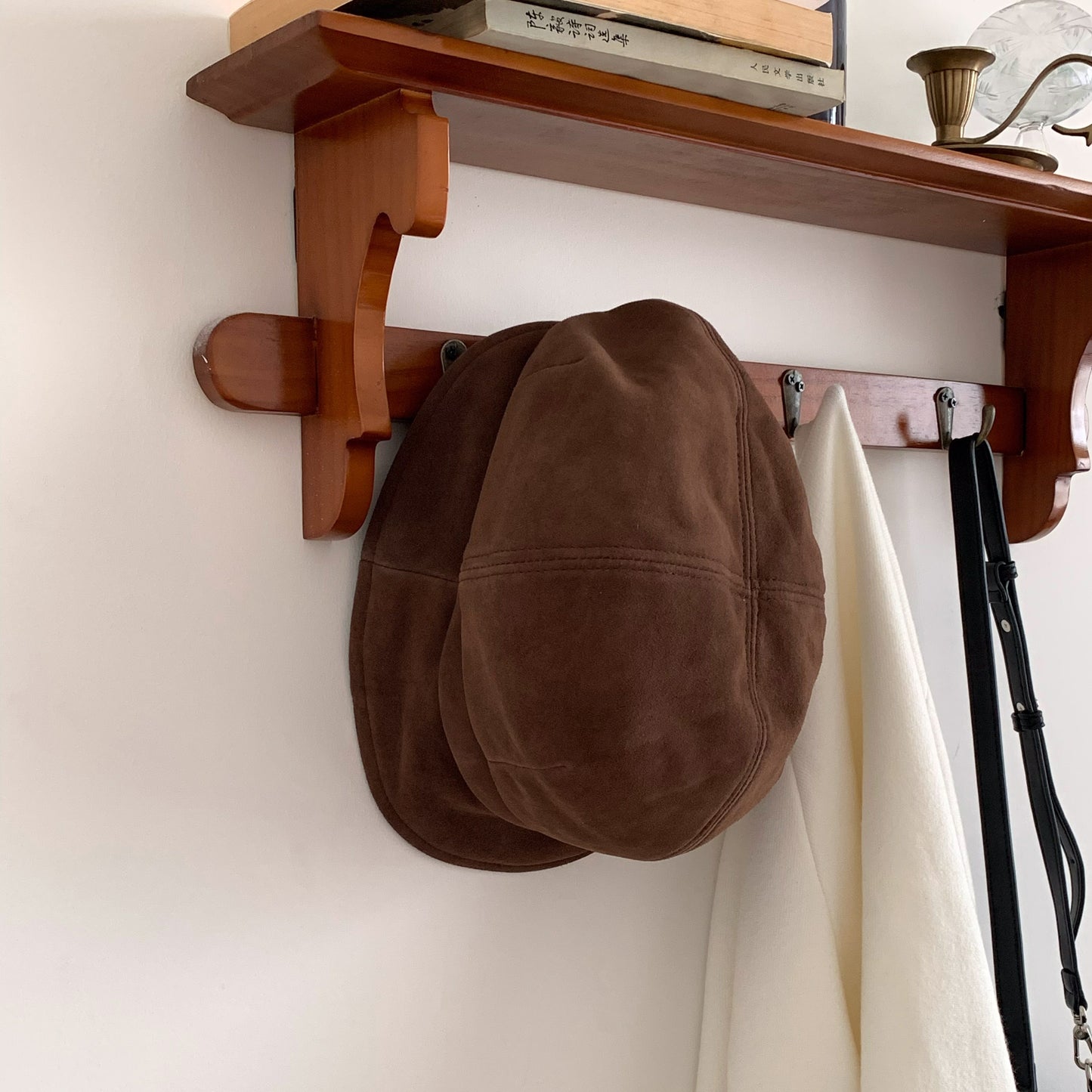 Brown paneled beret cap hanging on a wooden coat rack