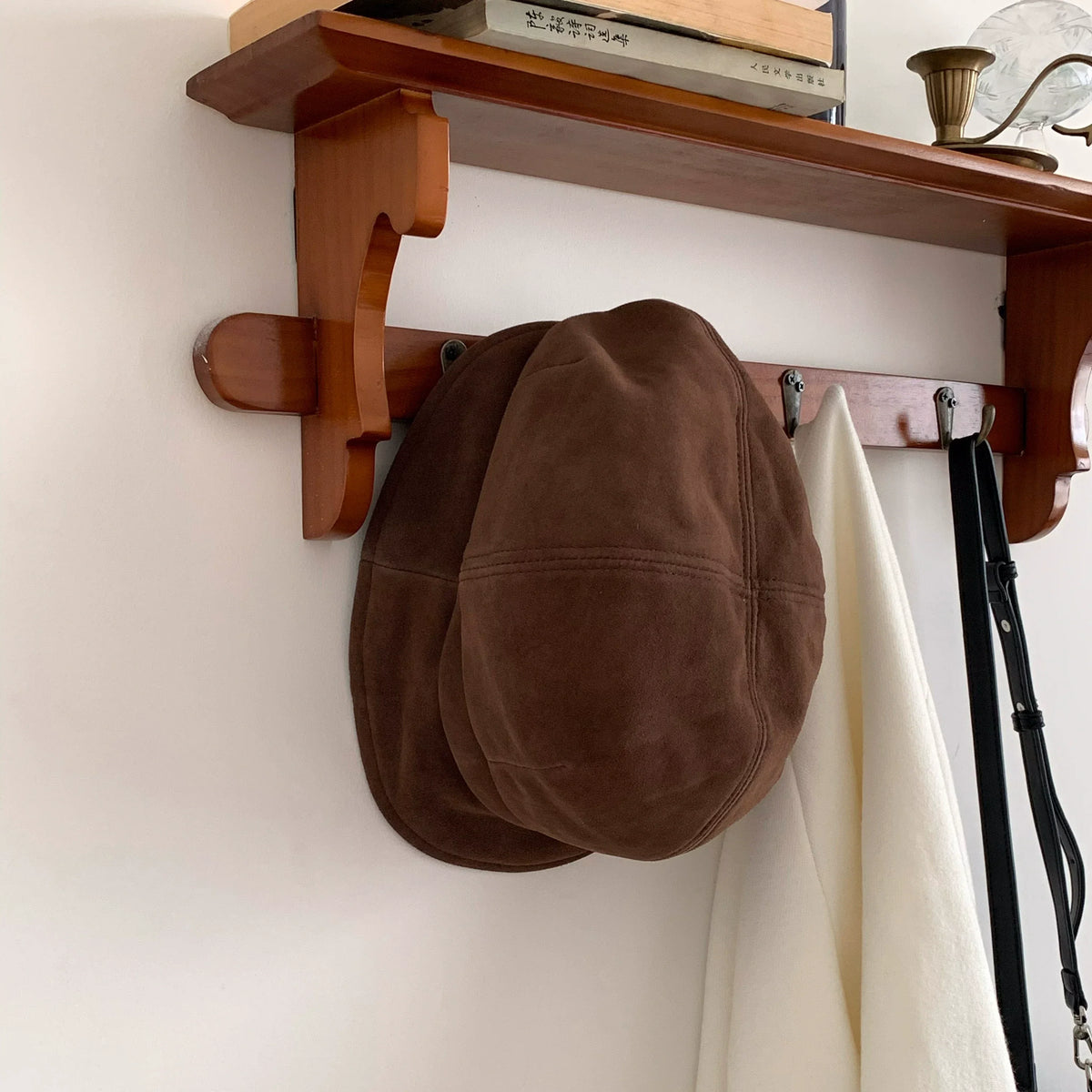 Brown paneled beret cap hanging on a wooden coat rack