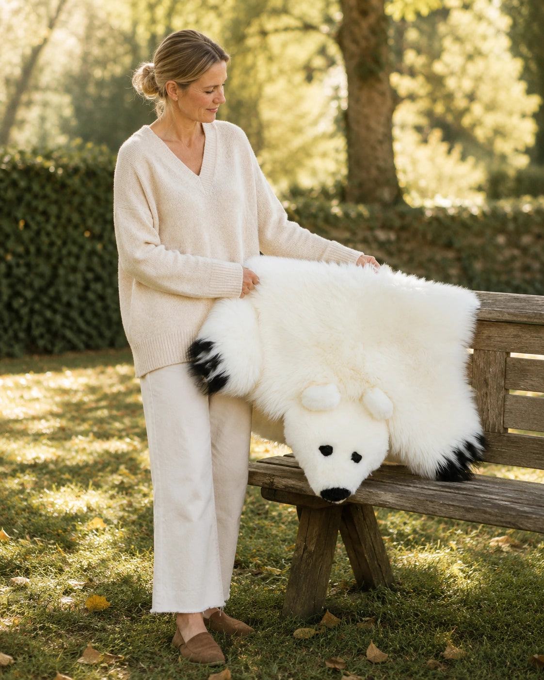 Adult woman holding a white bear-shaped genuine wool rug outdoors