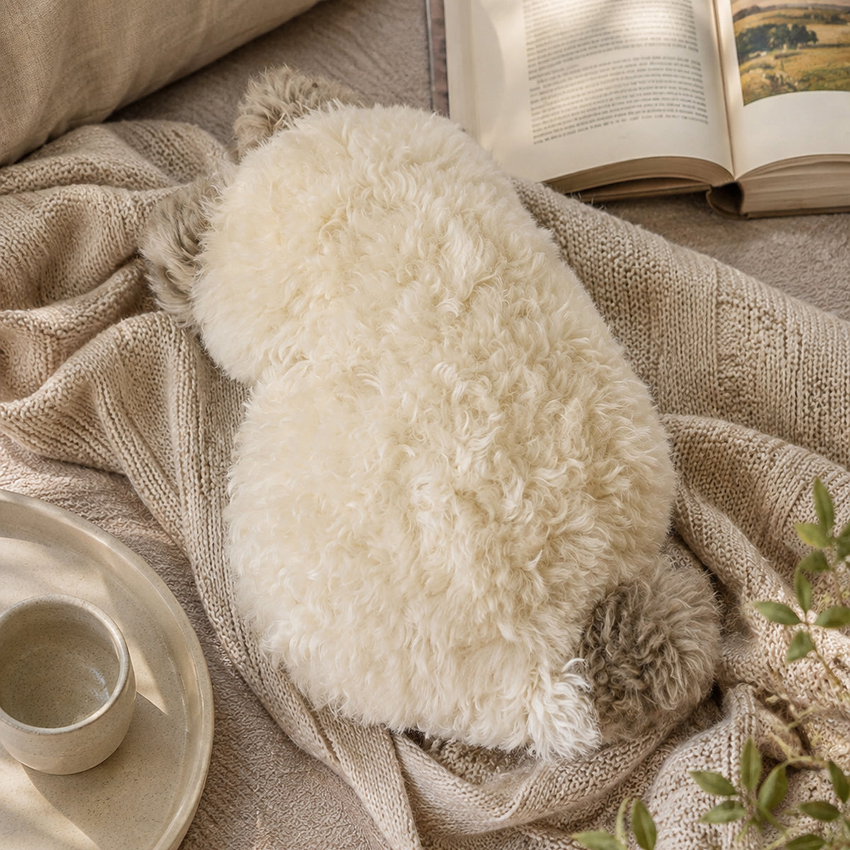 Cat-shaped plush cushion arranged with soft neutral textiles
