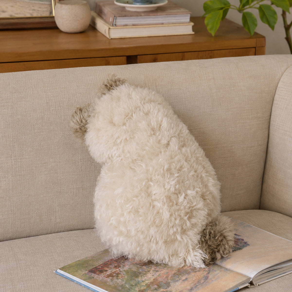 Cat-shaped plush cushion in a calm neutral sofa setting