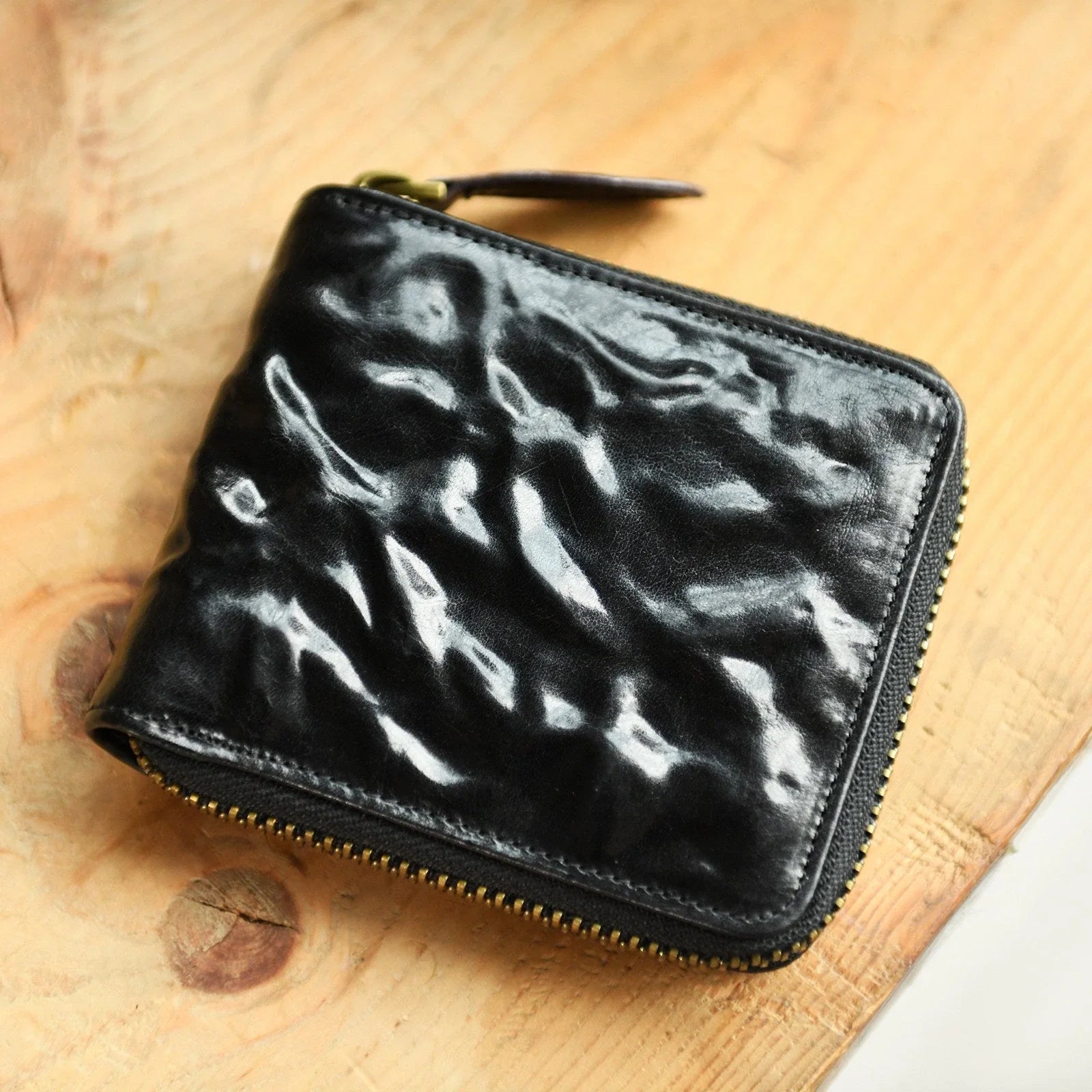 Black top-grain cowhide zip-around wallet with hand-creased texture