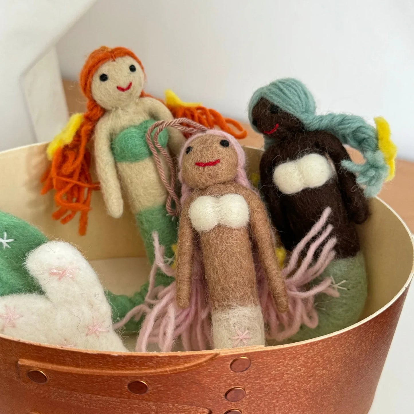 Handmade wool felt mermaid charms arranged in a warm interior