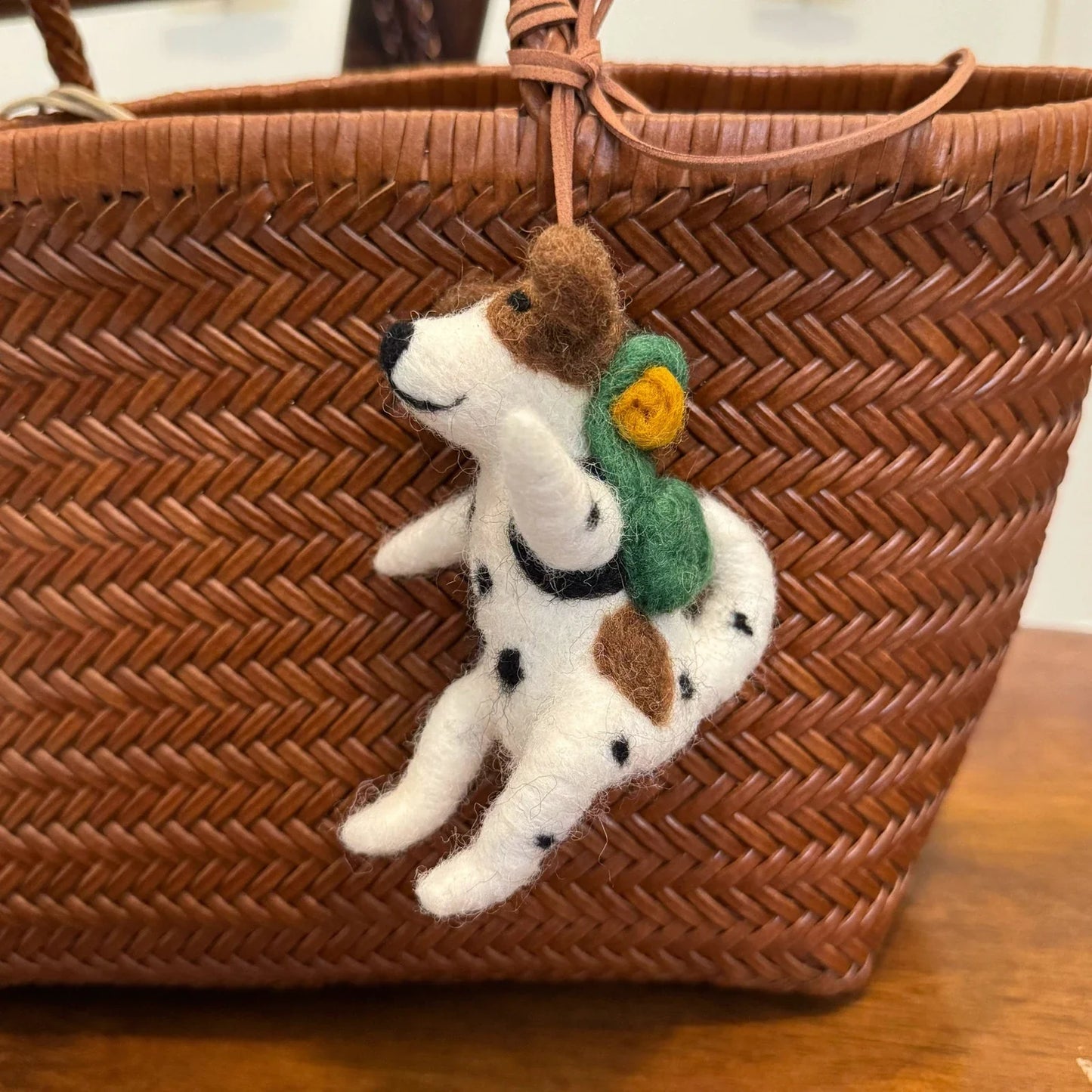 Handmade wool felt Dalmatian charm hanging from a woven bag