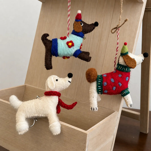 Handmade wool felt dog ornaments displayed on natural wood
