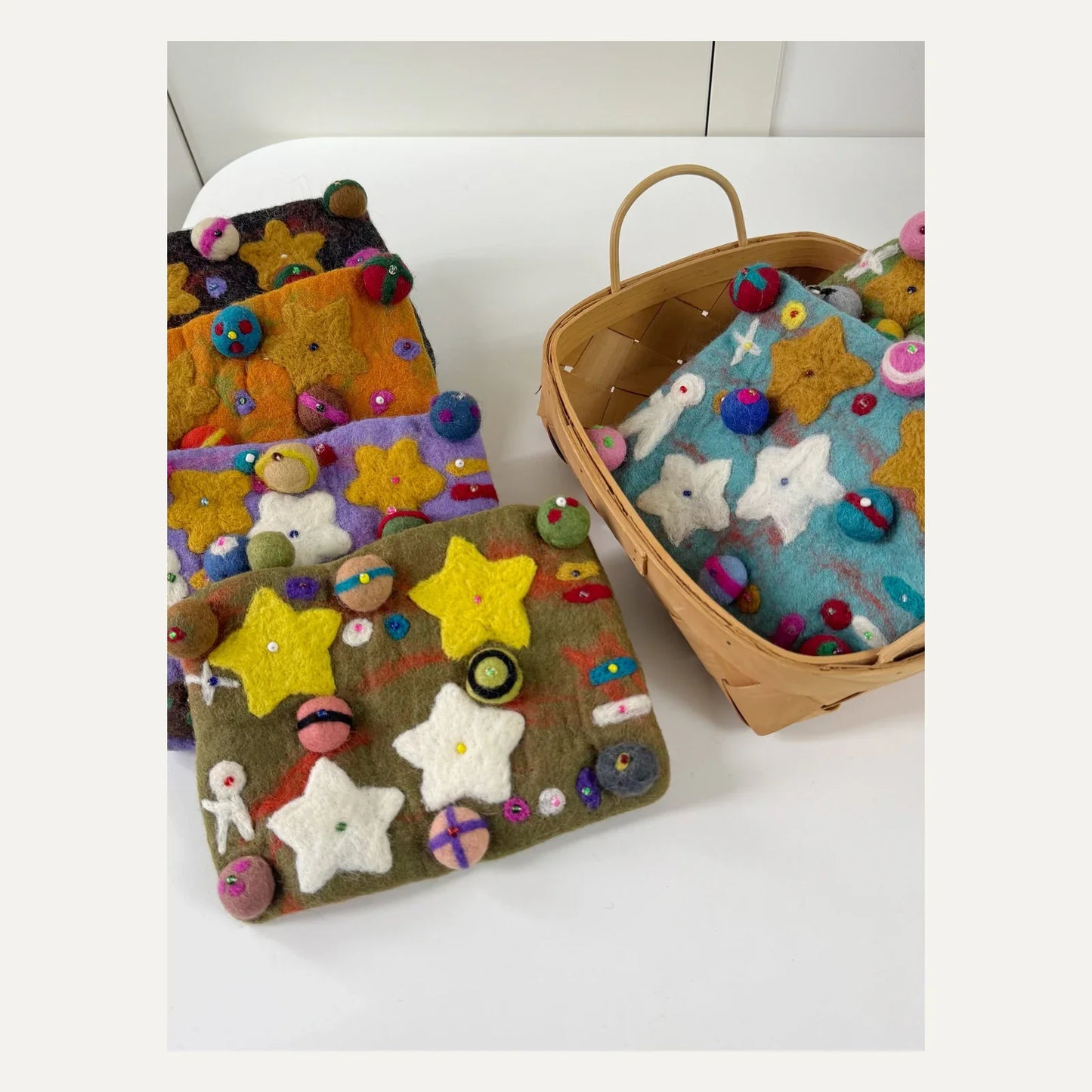 Handmade wool felt planet crossbody bags arranged in a colorful collection