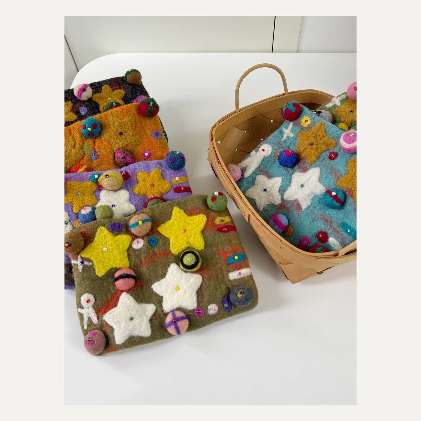 Handmade wool felt planet crossbody bags arranged in a colorful collection