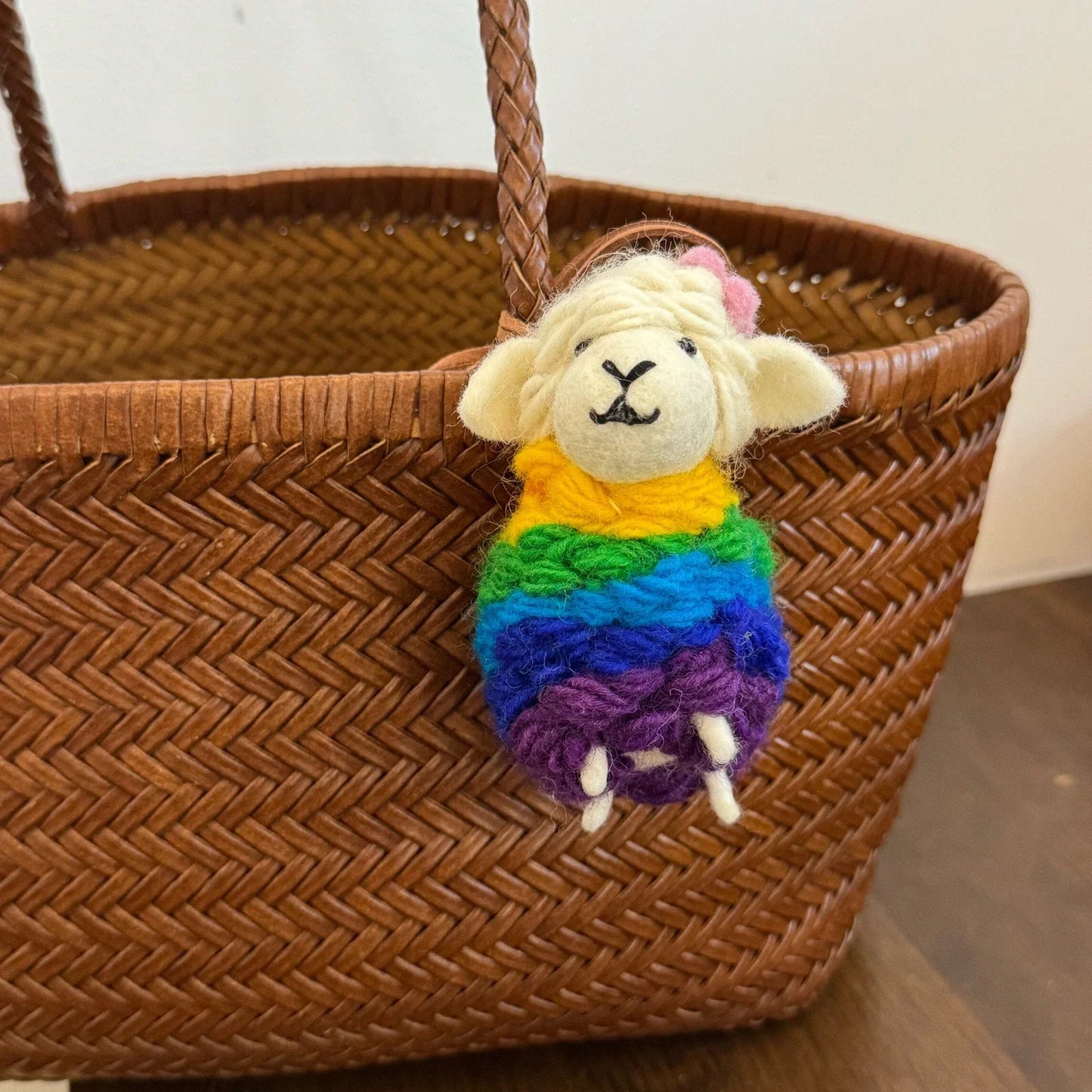 Cream wool felt sheep charm wearing a rainbow knitted wrap