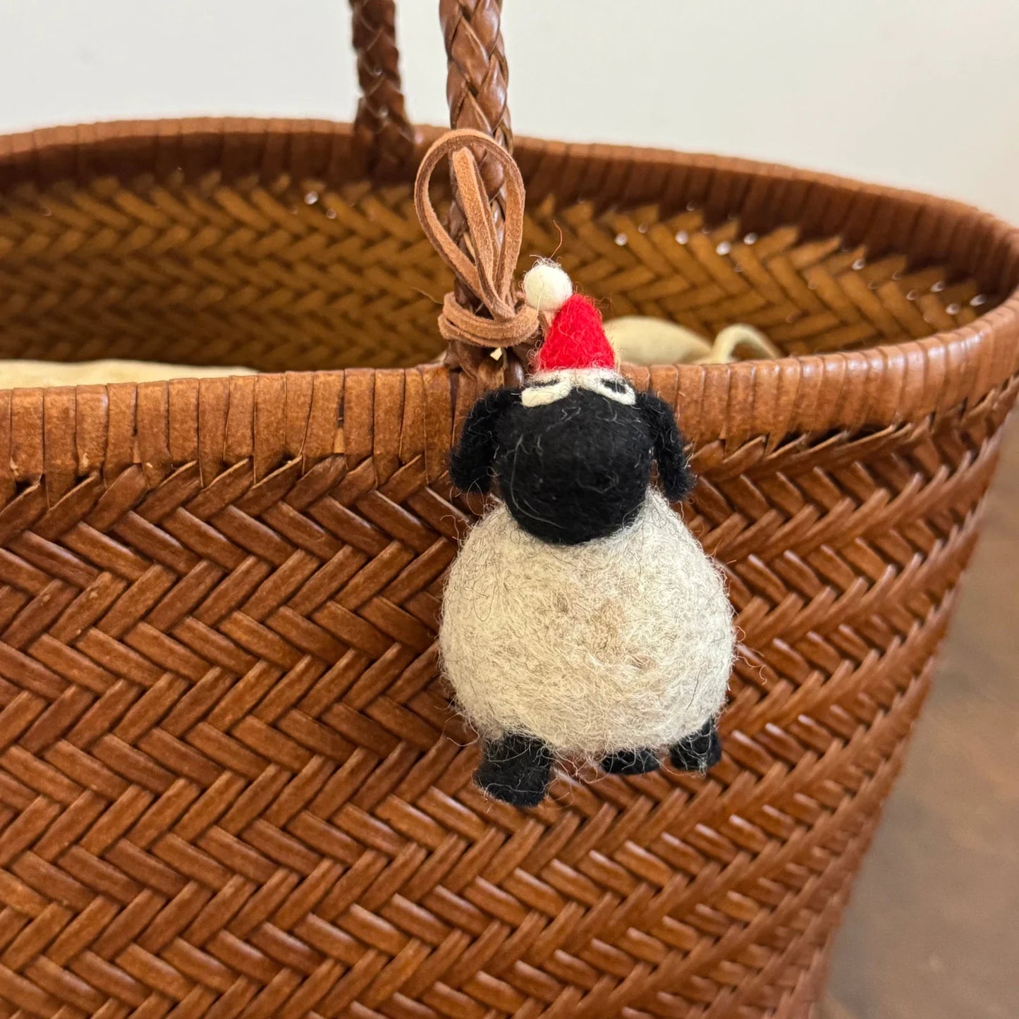 Gray faced wool felt sheep charm wearing a red pompom hat