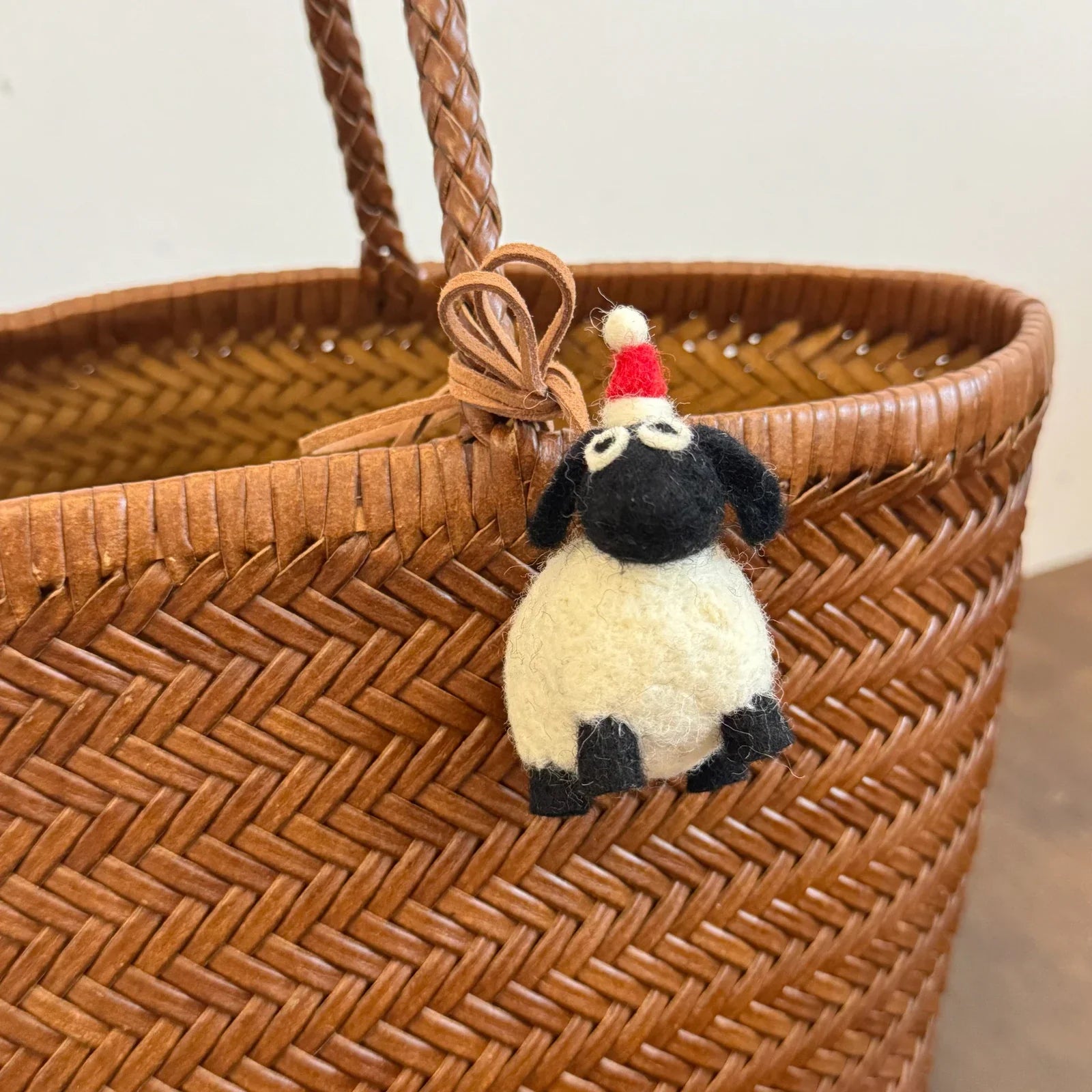 White wool felt sheep charm with black face and red pompom hat