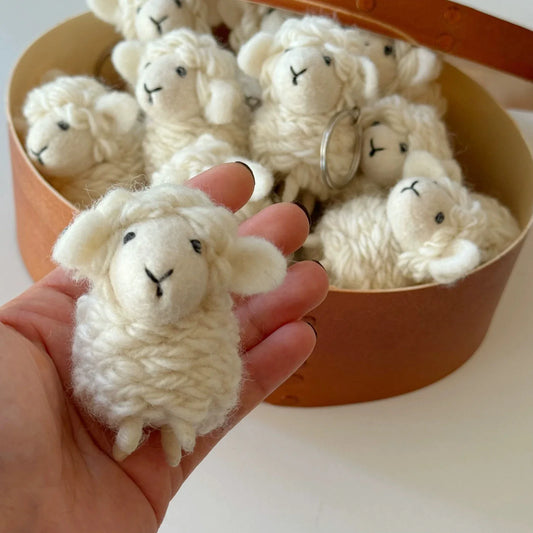 Handheld detail of a handmade wool felt sheep charm