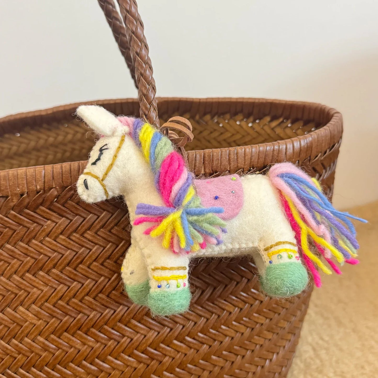 Close-up of multicolor wool felt horse bag charm with leather rope loop