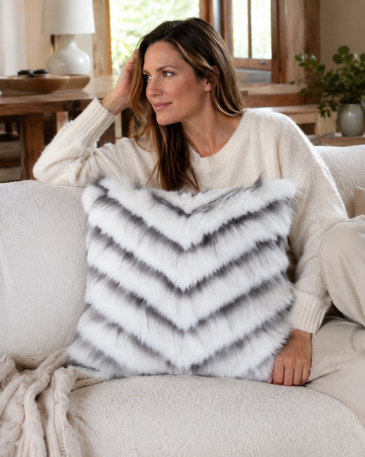 Capricornus Living Adult relaxing with an Ivory White square genuine fur chevron pillow on a sofa