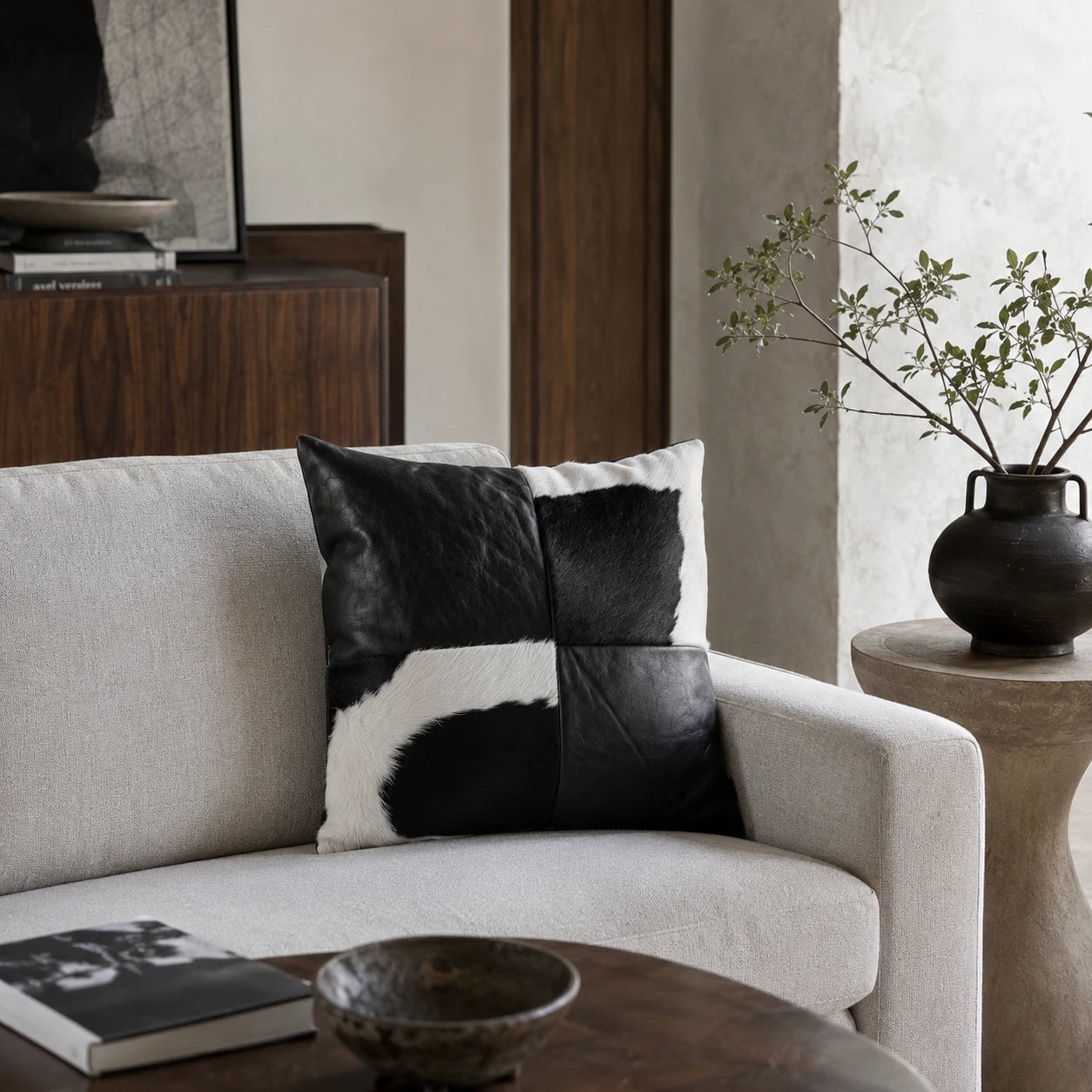 Obsidian black leather and cowhide square pillow styled on an ivory sofa