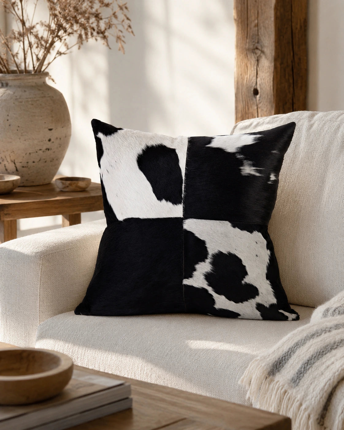 Capricornus Living Four-Panel Black and White genuine cowhide square pillow styled on a linen sofa