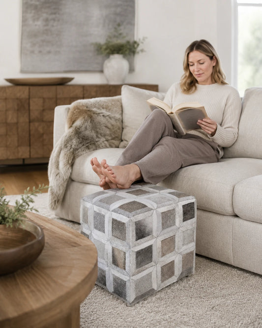 Capricornus Living Silver Gray cowhide square ottoman shown at scale as a sofa footrest