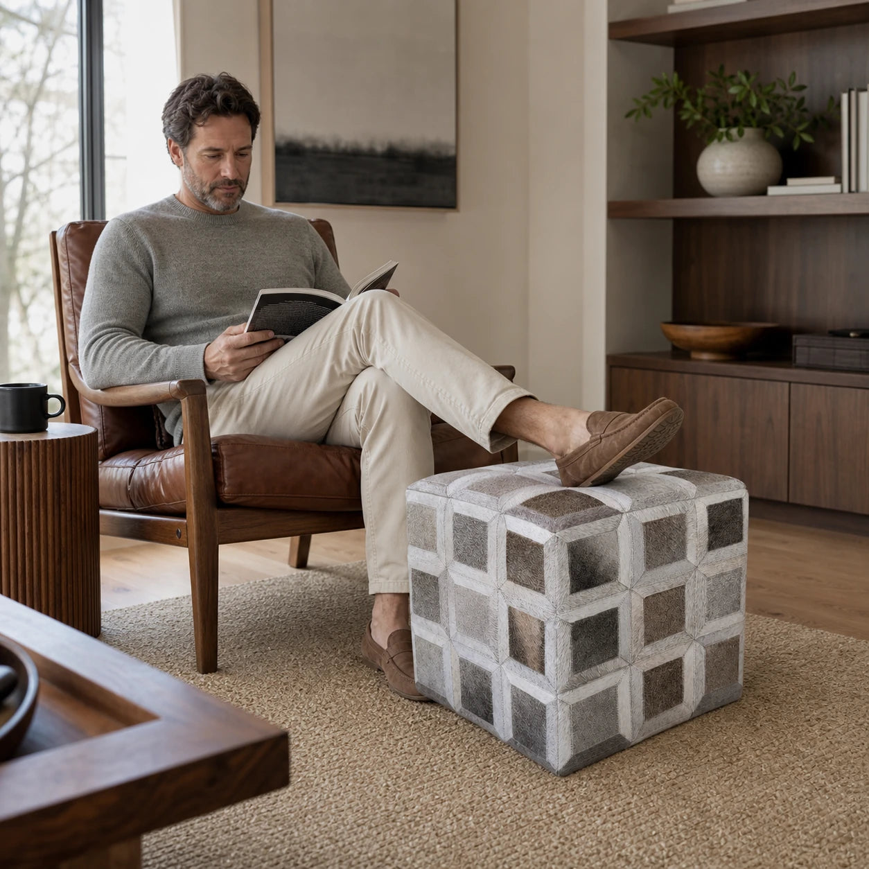 Capricornus Living Silver Gray cowhide square ottoman used as a footrest in an American reading room