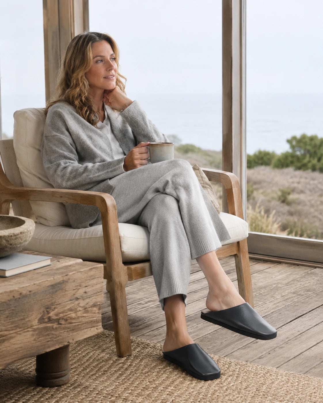Capricornus Living Black leather house slippers worn beside a window chair