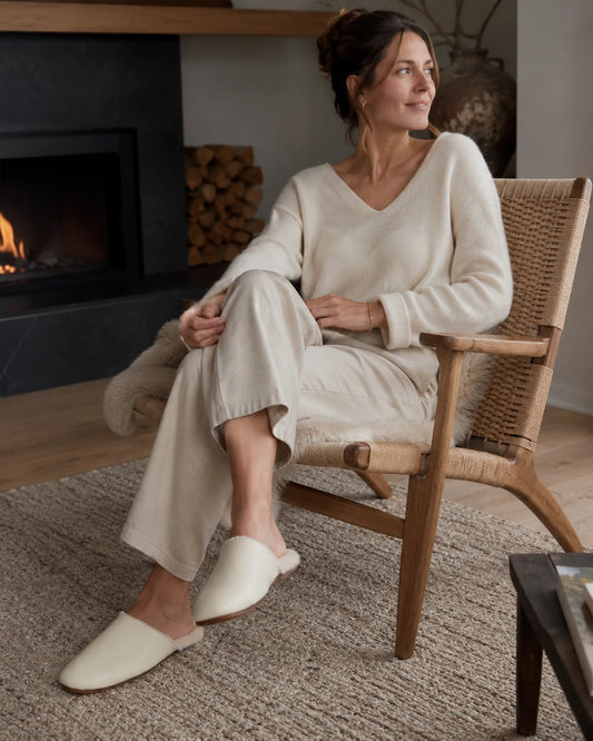 Capricornus Living Ivory lambskin plush-lined slippers worn beside a reading chair