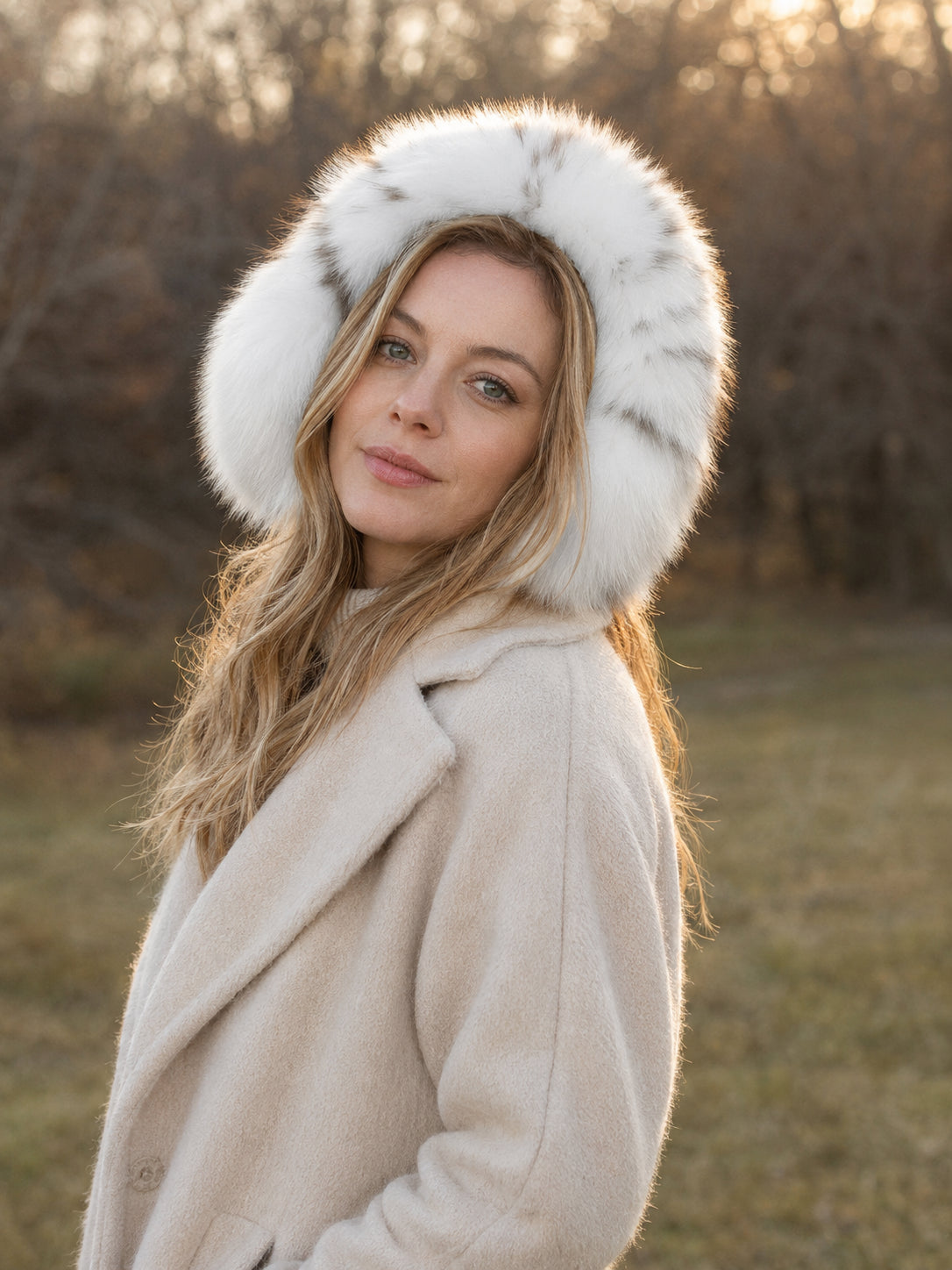 Woman wearing White Leopard fox fur earmuffs in a woodland setting