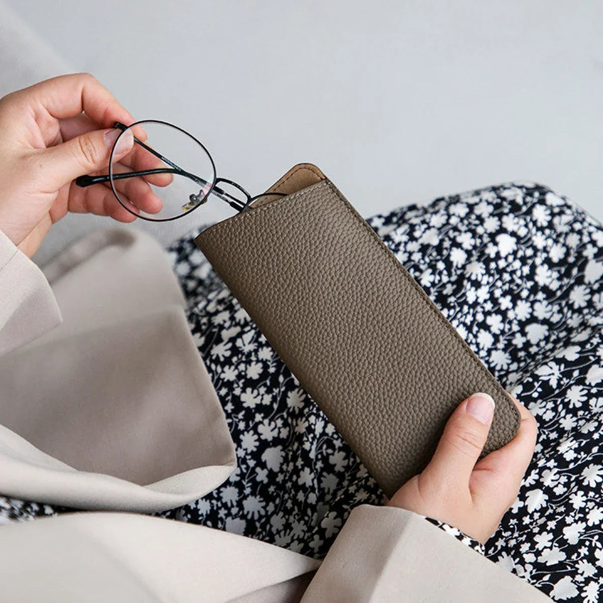 Eyeglasses being placed into a pebbled cowhide sleeve