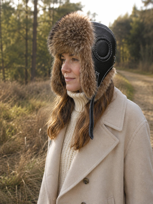 Woman wearing a raccoon dog fur and black sheepskin leather trapper hat on a forest walk