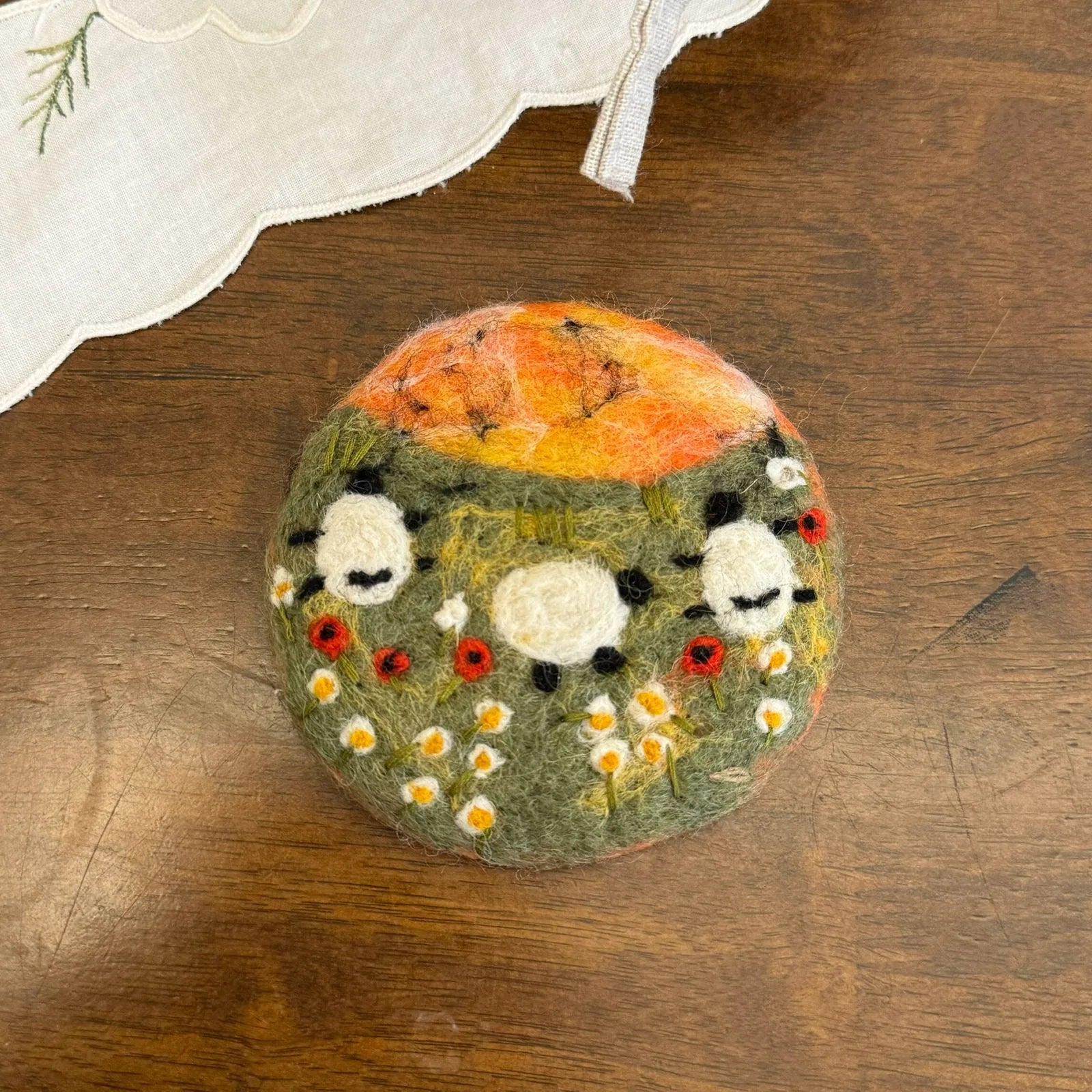Sunset wool felt coaster with sheep, flowers and warm orange mountains