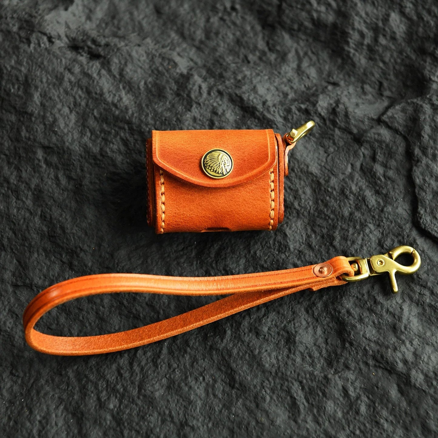 Sunset Tan cowhide earbud case with heritage medallion and wrist strap