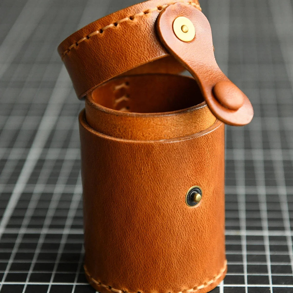 Open cylindrical leather storage case showing the single compartment