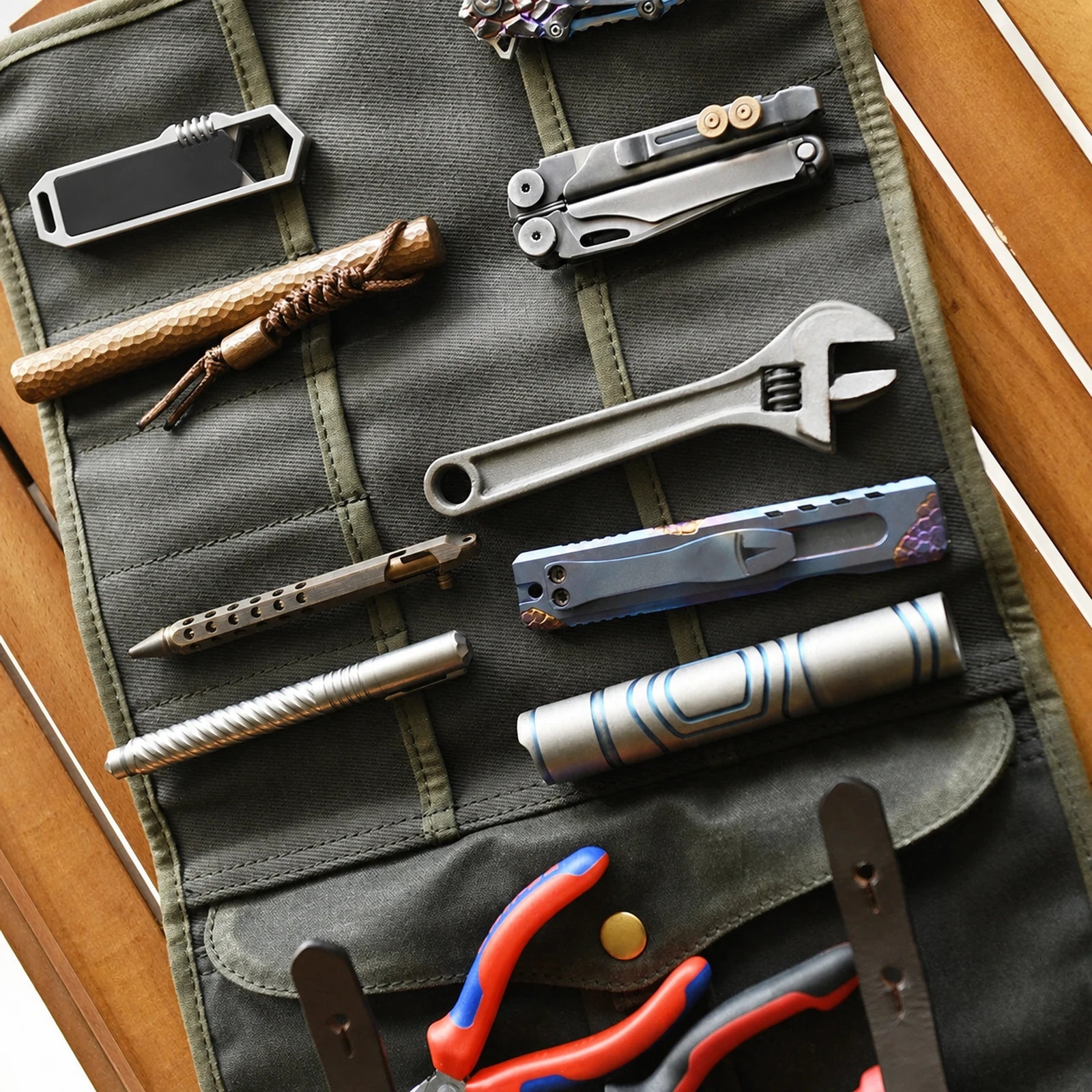Waxed canvas and cowhide roll-up tool organizer open with unbranded hand tools arranged in its pockets