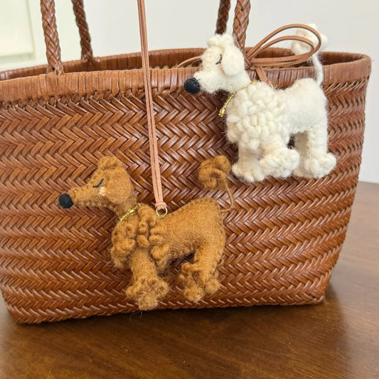 White and brown wool felt poodle charms styled on a woven bag