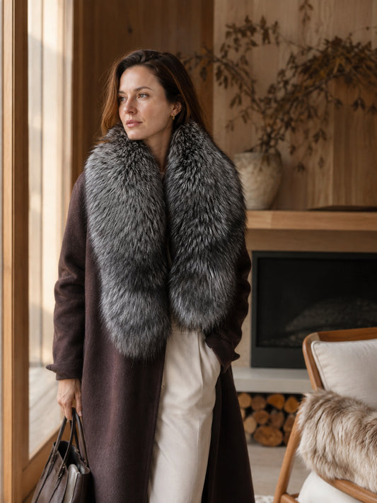Woman wearing a natural Finnish silver fox fur scarf beside a fireplace