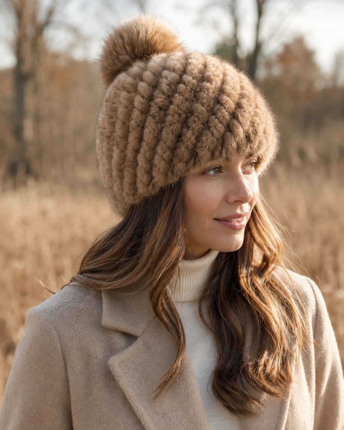 Light natural brown genuine mink fur knitted beanie with fox fur pom-pom worn outdoors