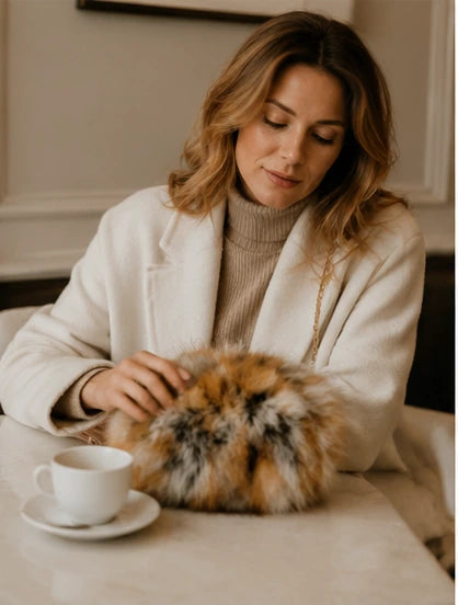 Red fox fur hand muff bag used at an indoor cafe table