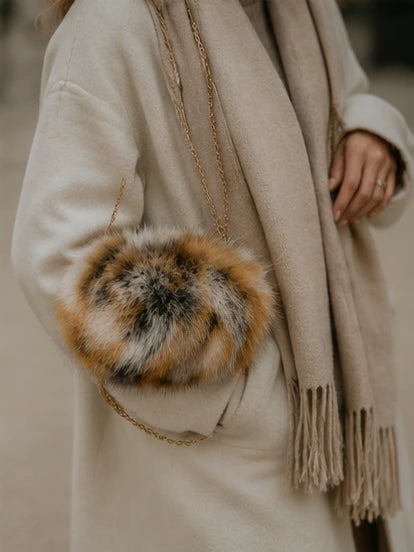 Close view of a red fox fur hand muff chain bag with a cream winter coat