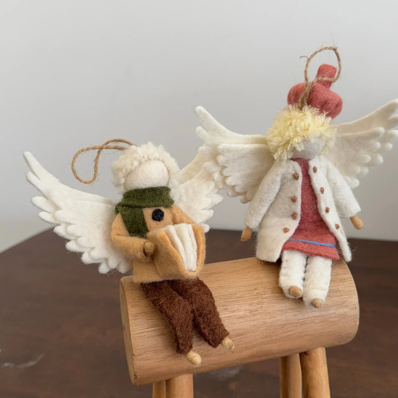 Two handmade wool felt angel bag charms with stitched clothing details