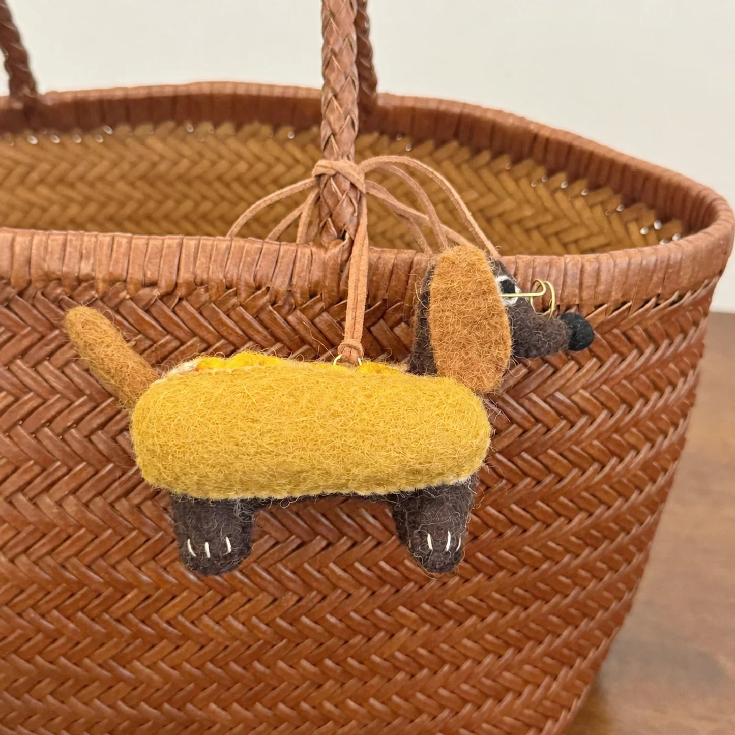 Close view of wool felt dachshund bag charm on a woven bag