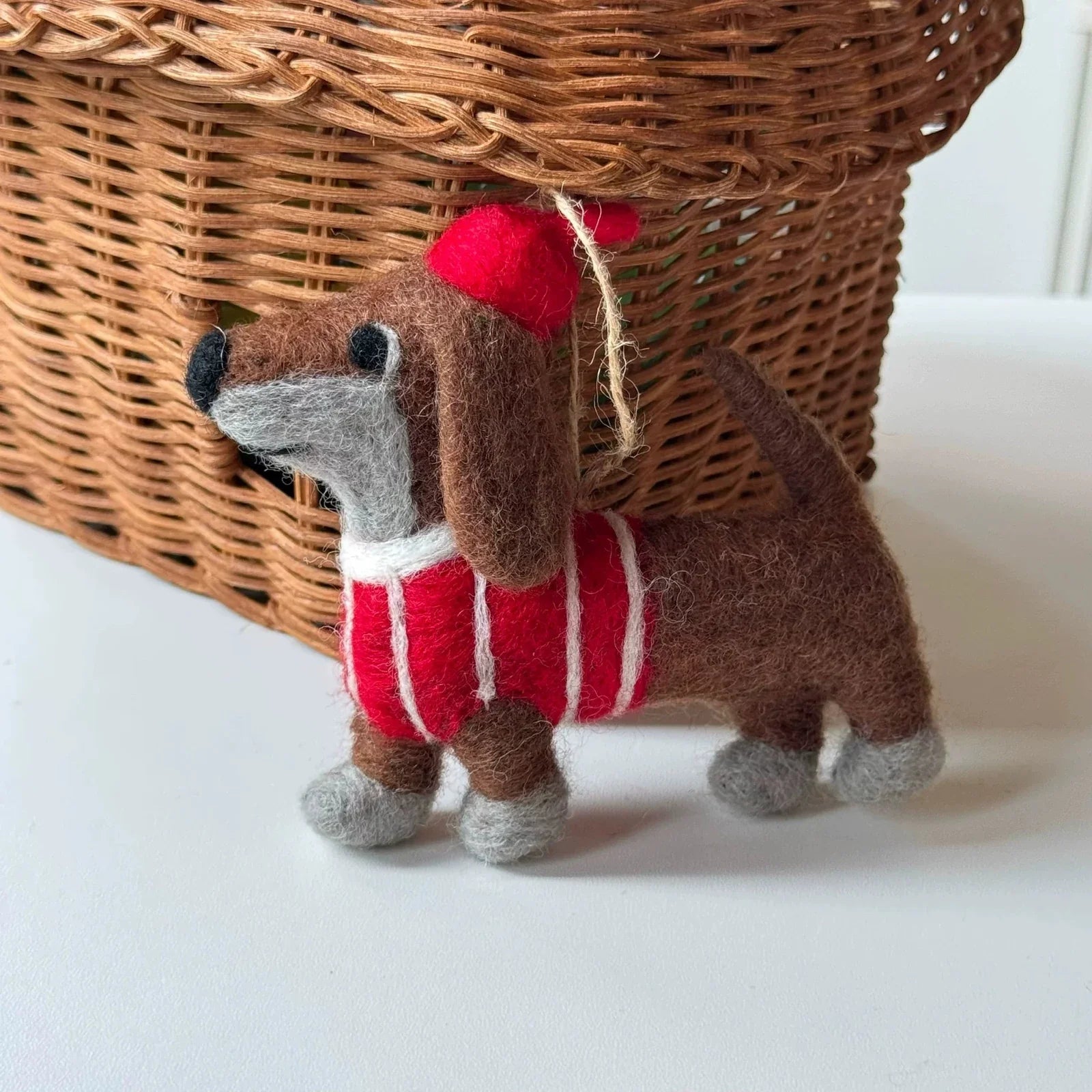Full view of a brown wool felt dachshund charm in a striped sweater