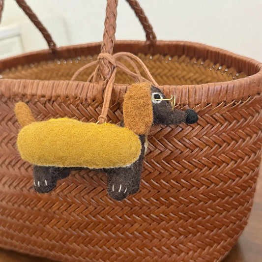 Wool felt dachshund charm styled on a woven basket bag
