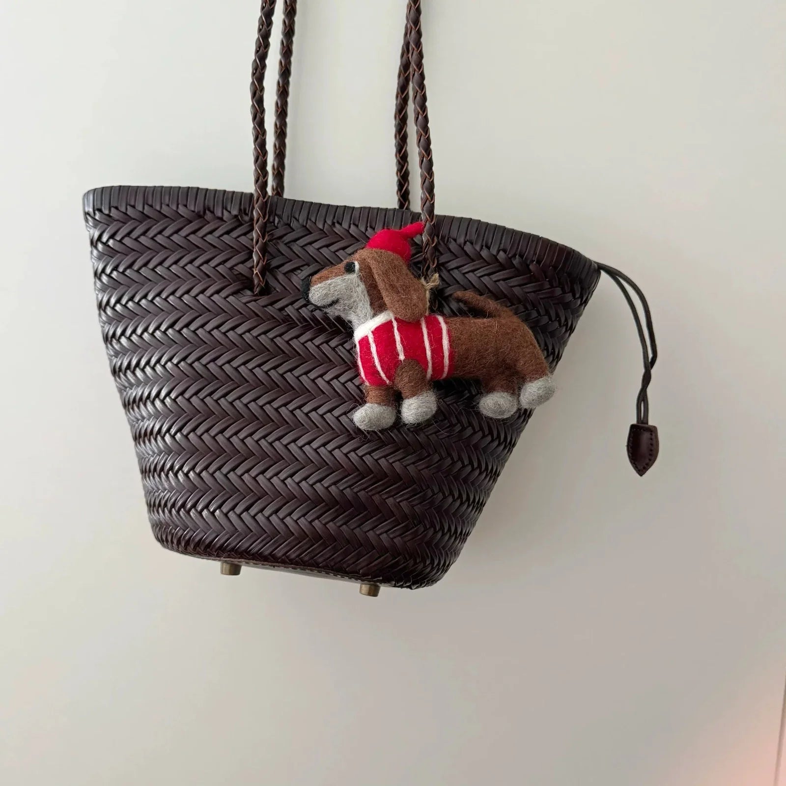 Wool felt dachshund charm styled on a dark woven basket bag