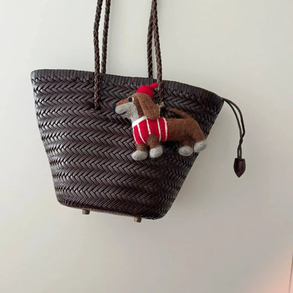 Wool felt dachshund charm styled on a dark woven basket bag