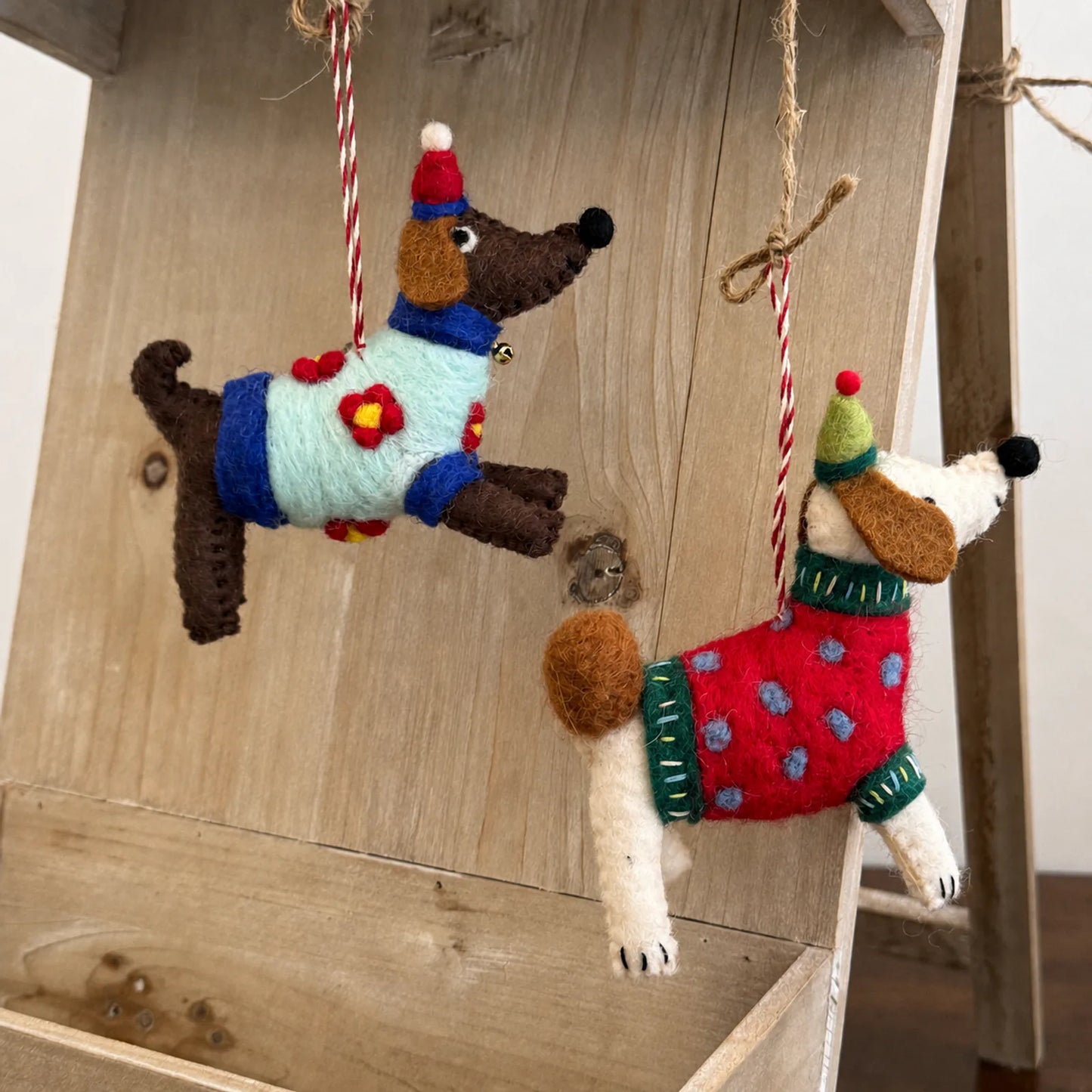 Colorful wool felt dog charms hanging in a warm lifestyle setting