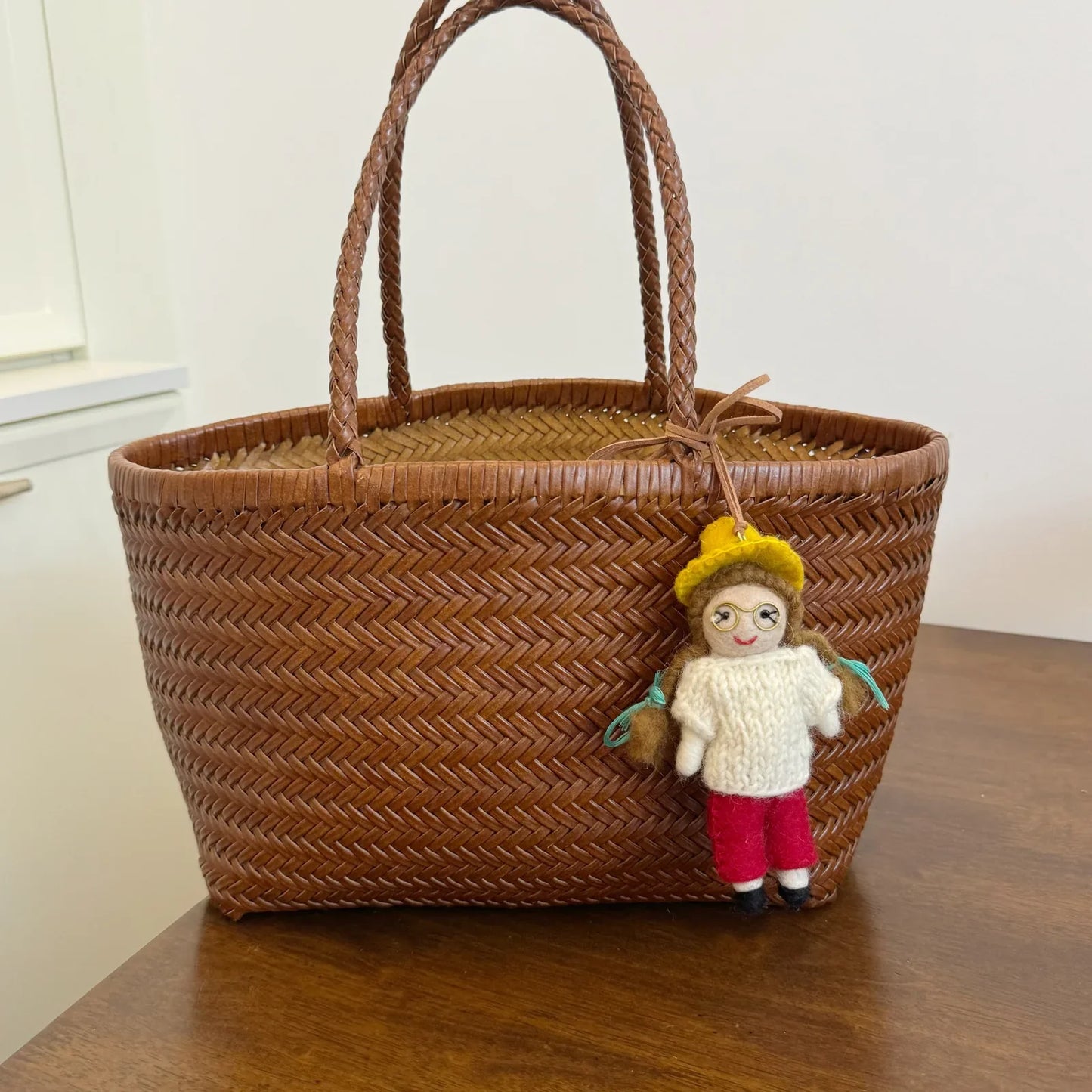 Handmade wool felt ponytail girl charm styled on a woven bag